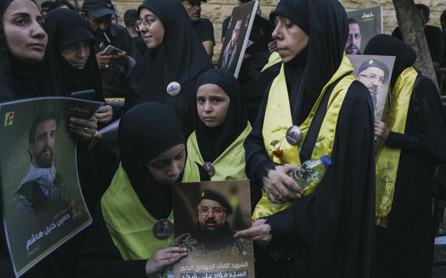 Mourners hold posters of Fuad Shukr, a top Hezbollah military commander who was killed in an Israeli airstrike, during his funeral in a Beirut suburb.