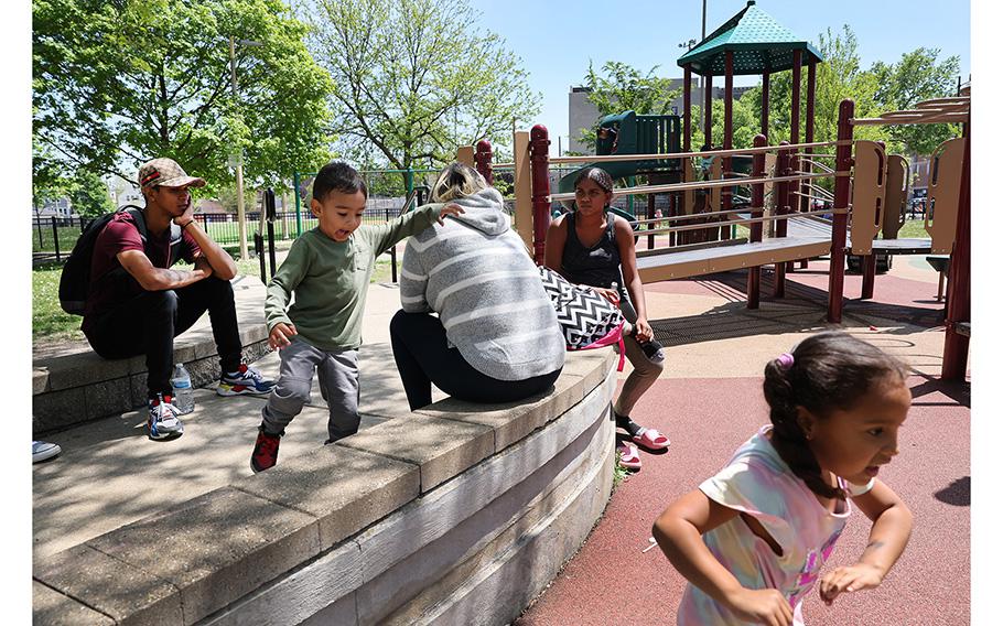 Migrant families from Venezuela watch as their children play in the playground at Brands Park on May 10, 2023, in Chicago, Illinois. 