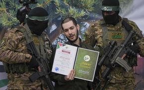 Israeli hostage Eliya Cohen, center, is instructed to show a Hamas issued certificate while being escorted by militants.