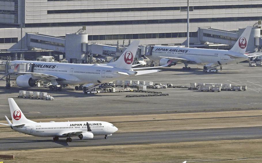 Three Japan Airlines airplanes, including one on the runway, are seen at the Haneda airport in Tokyo.