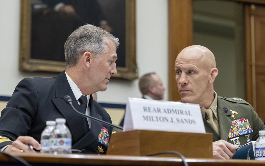 Two men in uniforms seated at a table chatting.