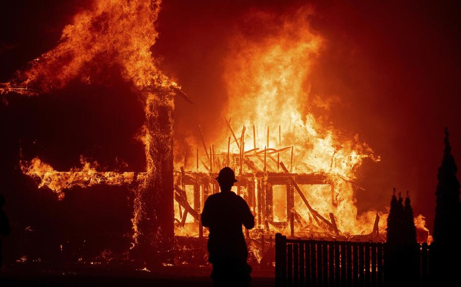 A California firefighter watches a house engulfed in flames.