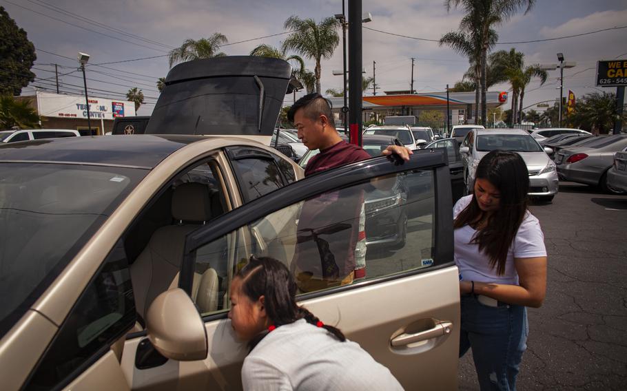 Lei and his family look at a secondhand car in an auto service shop.