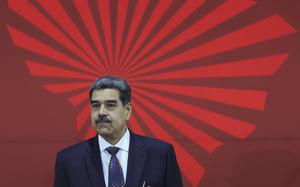 Nicolas Maduro in a suit in front of a red background and graphic.