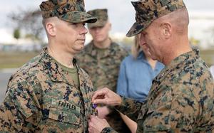 Brig. Gen. Kevin Collins, commander of the 3rd Marine Logistics Group, presents a Purple Heart to Chief Warrant Officer 2 William Faffler at Camp Kinser, Okinawa, Jan. 6, 2025.