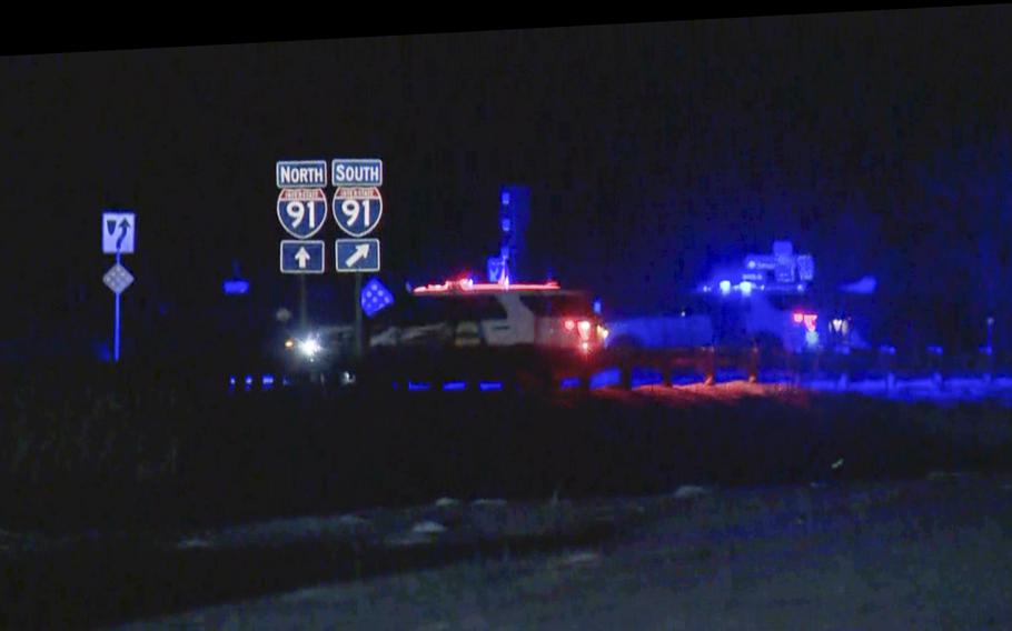 Police cars and lights near signs marking Interstate 91 near the Canadian border in Vermont.