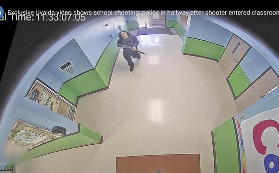 FILE - In this image from surveillance video provided by the Uvalde Consolidated Independent School District via the Austin American-Statesman, a gunman carrying an AR-15 style rifle enters and walks down a hallway at Robb Elementary School in Uvalde, Texas, Tuesday, May 24, 2022.  (Uvalde Consolidated Independent School District/Austin American-Statesman via AP, File)