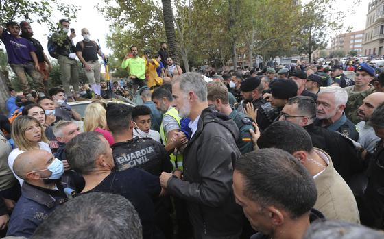 Spain's King Felipe VI, centre, leaves the scene after crowd of angry survivors of Spain's floods have tossed mud and shouted insults at the King and government officials when they made their first visit to one of the hardest hit towns. after floods in Paiporta near Valencia, Spain, Sunday, Nov. 3, 2024. (AP Photo/Hugo Torres)