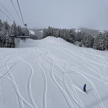 A view of the slopes at Breckenridge ski resort, including a chairlift and snowboarder. 