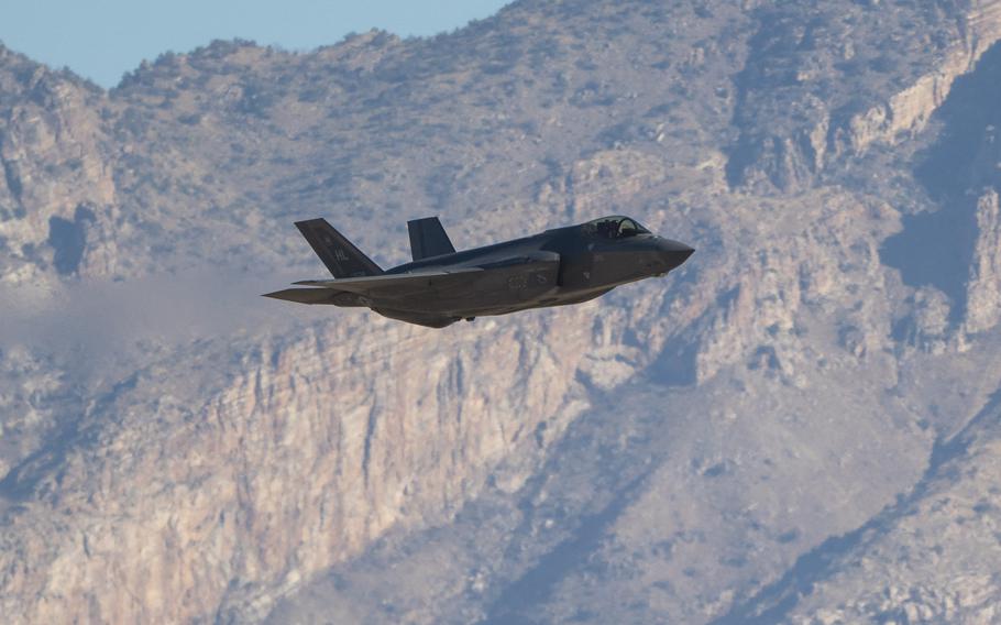 An F-35 in flight, mountains in the background.