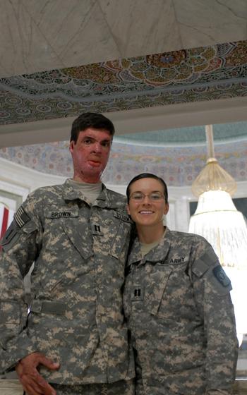 Brown and his wife stand next to each other, posing in their Army uniforms.