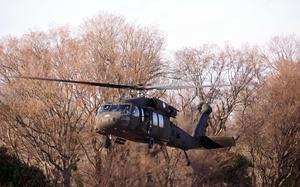 A Black Hawk helicopter is shown in front of trees.