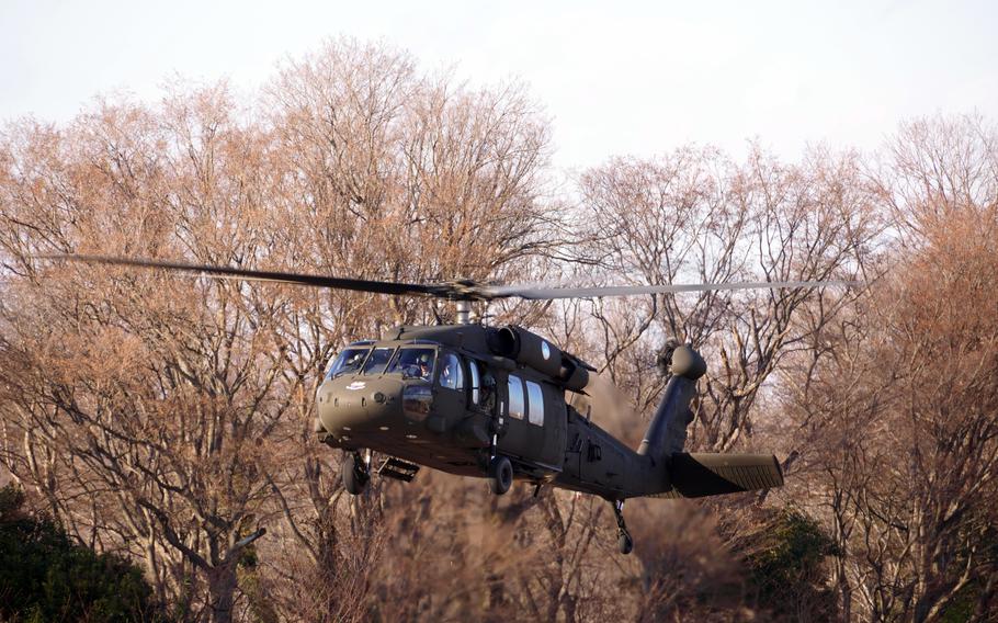 A Black Hawk helicopter is shown in front of trees.