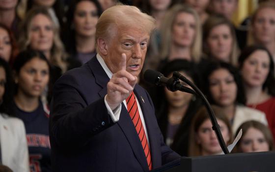 Donald Trump gestures with an outstretched hand while standing at a podium and speaking into a microphone.