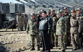 A man stands with a group of military members outside, looking off together.