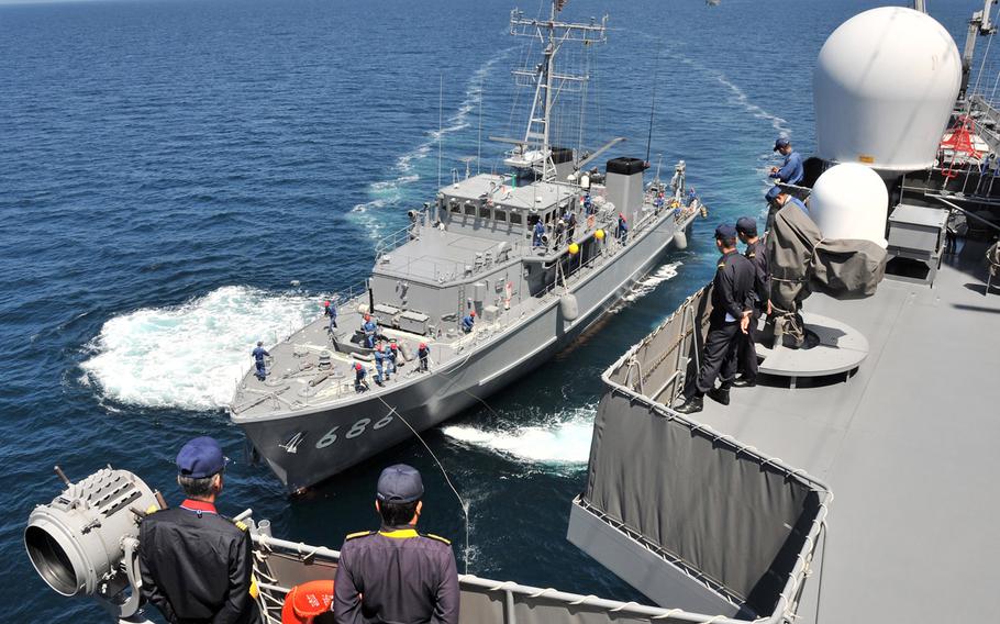 A minesweeper is surrounded by sailors in the waters off Japan.