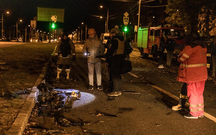 The pieces of a drone that damaged an apartment building in Kharkiv are examined on the street by emergency responders.