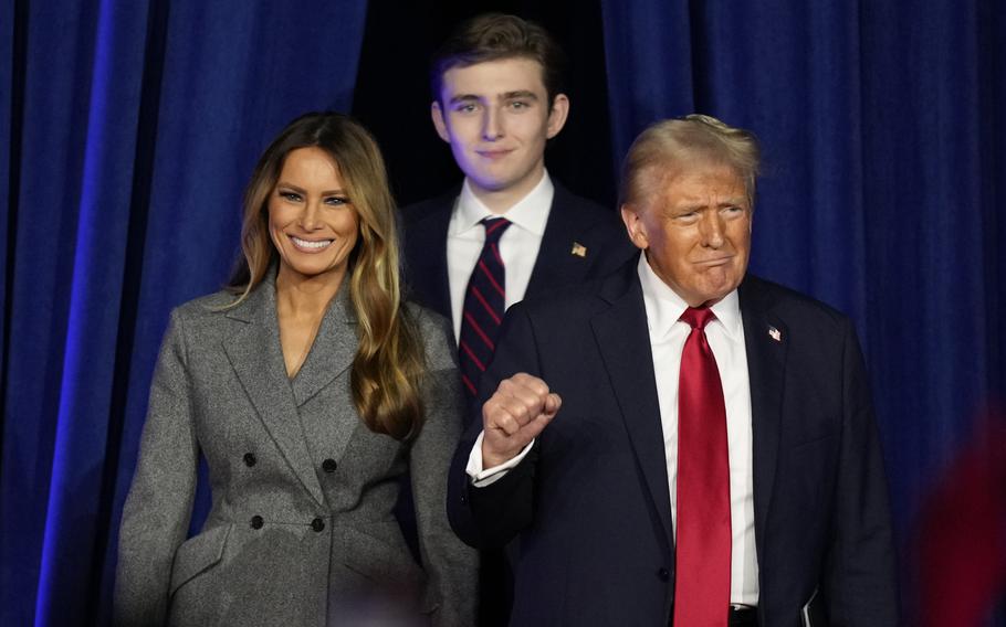 Donald Trump pumps his fist as he walks onto a stage with his wife Melania and son Barron.