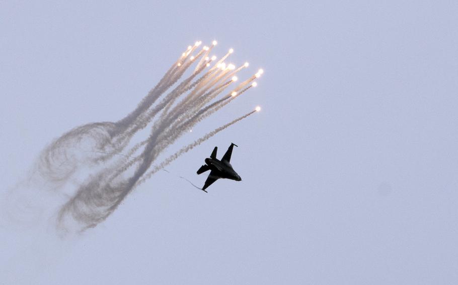 An F-16 flies next to several streaks of smoke.