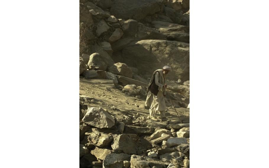 An elder man walking down a rocky mountain road 