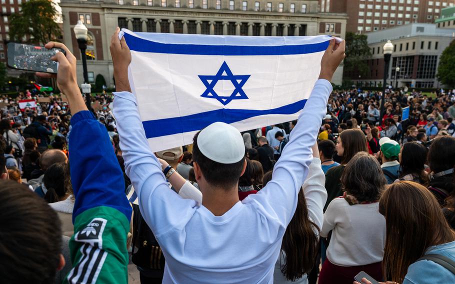 A man holds up an Israeli flag as Columbia students participate in a rally in support of Palestine at the university on Oct. 12, 2023, in New York.