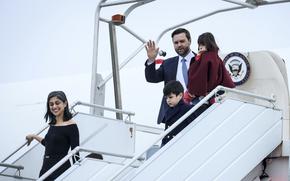 Vice President JD Vance holding his young daughter with one hand while descending stairs or an escalator; his son and wife are in front of him.