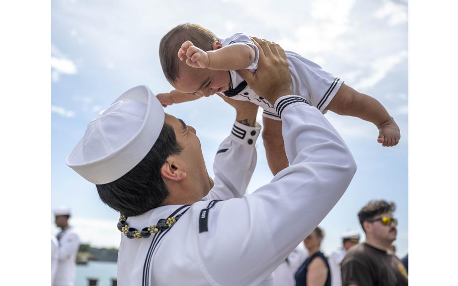 A sailor holds a baby in the air