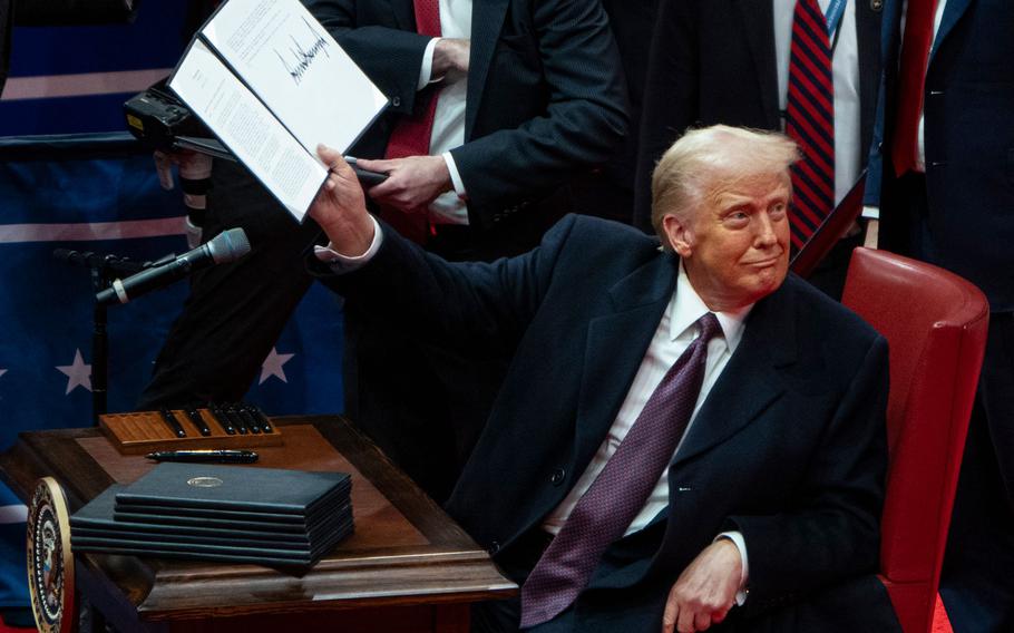 US President Donald Trump holds up an executive order he signed.