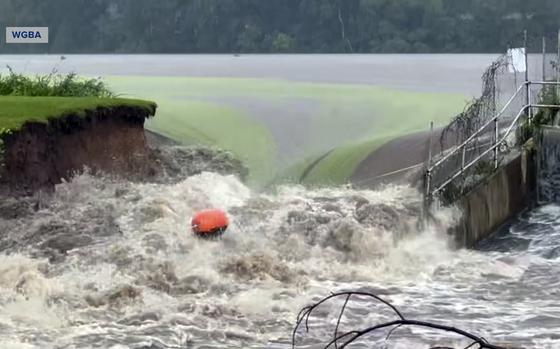 This image taken from video provided by WGBA-TV, shows water breaching a section of a dam along the Little Wolf River, Friday, July 5, 2024, in Manawa, Wis. (WGBA-TV via AP)