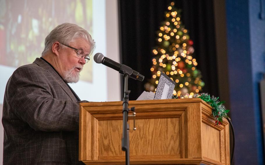 A historian in a suit speaks at a wooden podium.