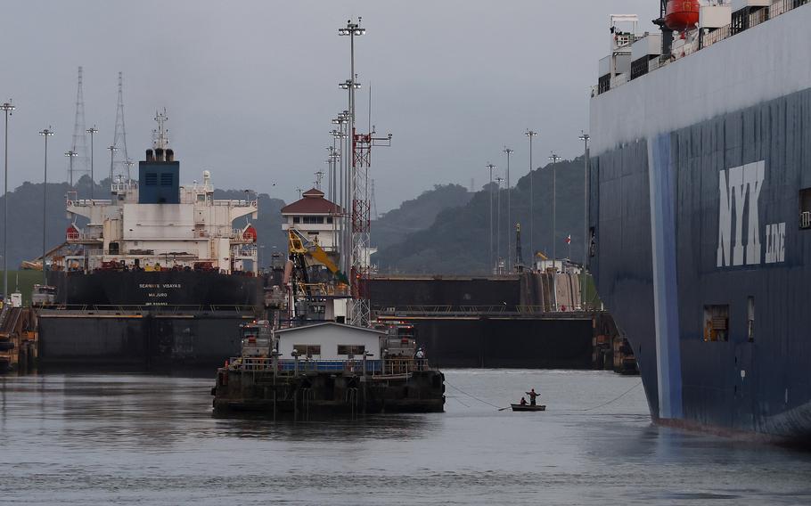 Dock workers on a small row boat pull a rope between the dock and vehicle carrier Sirius Leader as it prepares to enter the Miraflores locks while transiting the Panama Canal on Sept. 23, 2023, in Panama City, Panama. 