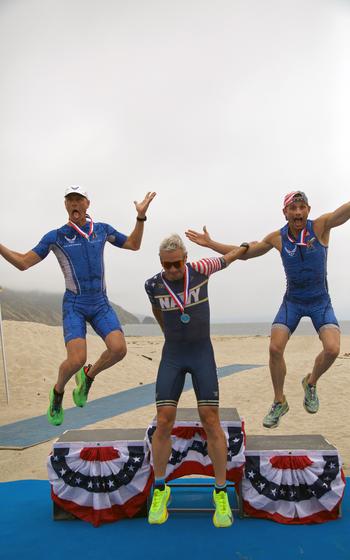 From left to right: Air Force Lt. Col. Jonathan Mason of Fort Liberty, N.C.; Navy Cmdr. Nicholas Collier; and Air Force Lt. Col. Kenneth Corigliano of Bolling AFB leap off the podium of the men’s masters division of the 2024 Armed Forces Triathlon Championships.