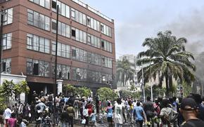 A group of people stand outside a damaged multi-story building.