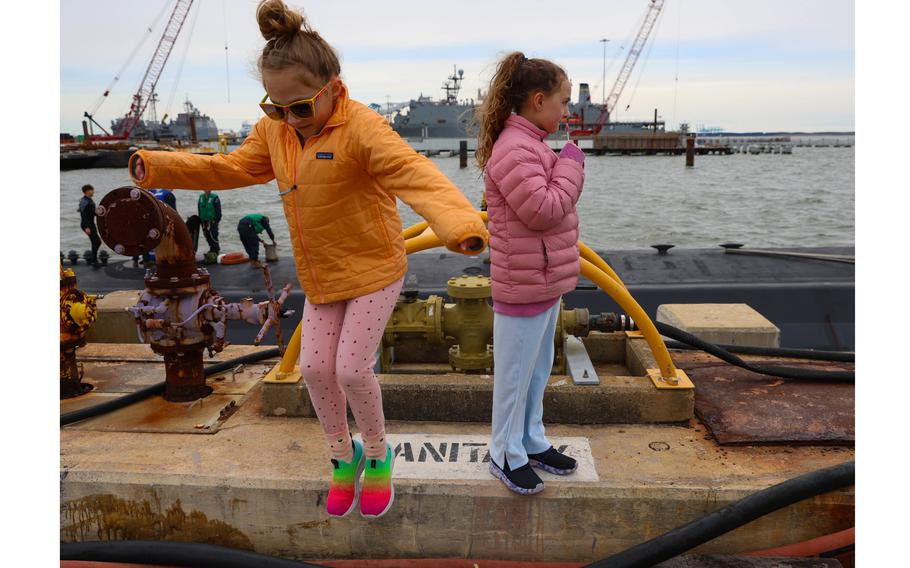 Two young girls jump around on the pier