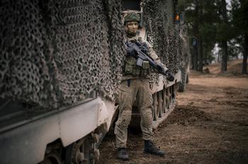 A Lithuanian soldier stands outside an M577 armored personnel carrier.