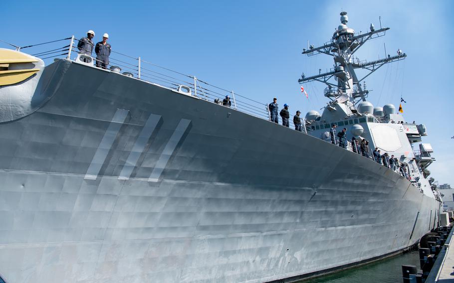 A view from the pier with sailors at the rail.