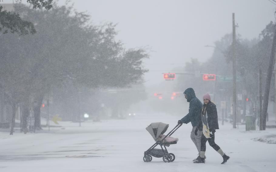 Snow and fog blur the lights as a couple push a stroller.