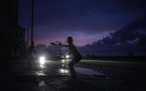 A woman prepares to catch a tossed frisbee during a massive blackout in Havana, Cuba, Oct. 18, 2024. 