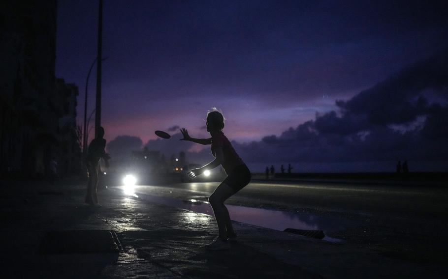 A woman prepares to catch a tossed frisbee during a massive blackout in Havana, Cuba, Oct. 18, 2024. 