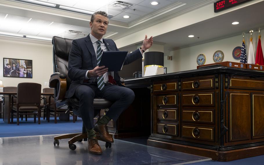 Pete Hegseth sits at a desk to record remarks about spending cuts.