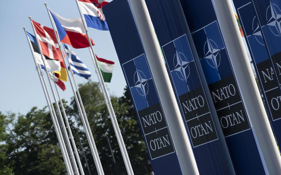 Several national flags of European countries next to banners with the NATO insignia.