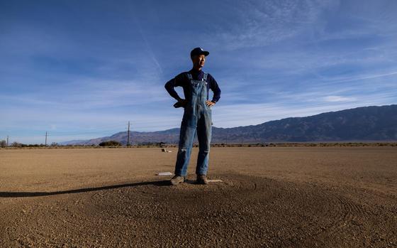 A man stands in the center of a sparse baseball diamond.