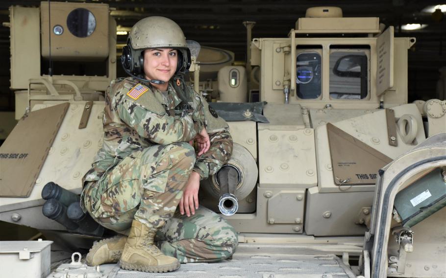 A female infantry officer with the Idaho National Guard crouches on an M2 Bradley Fighting Vehicle. 