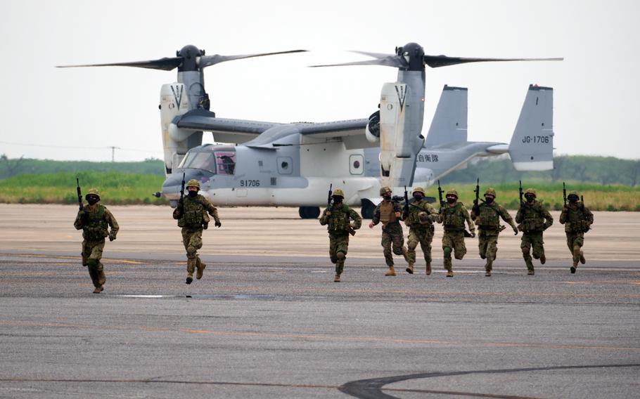 Soldiers run with their weapons from an Osprey aircraft.