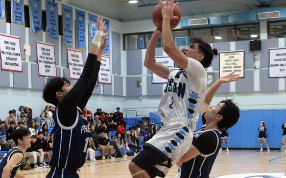 Osan's M.J. Siebert skies to shoot against two Korea International defenders.