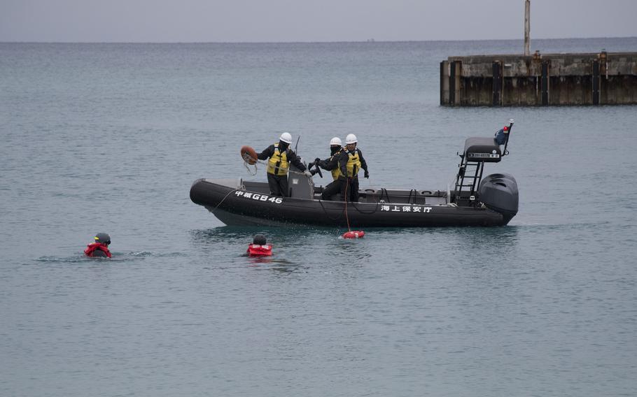 Japanese coast guard members in an inflatable boat rescue U.S. Navy divers acting as casualties.