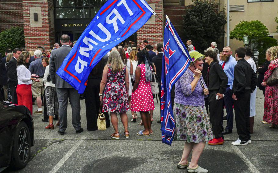 A Trump supporter holds flags June 27, 2023, while waiting in line to hear former president Donald Trump speak at a luncheon held by the New Hampshire Federation of Republican Women. The former president is polling very well in the race for the 2024 GOP presidential nomination despite a slew of legal trouble.