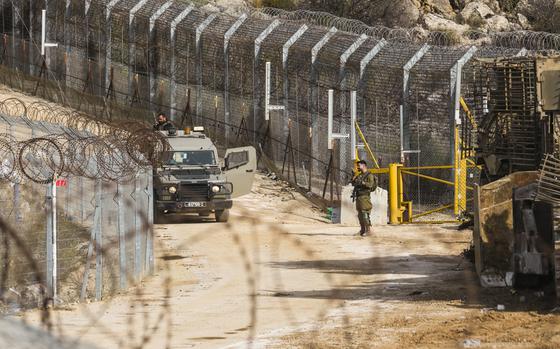 An Israeli soldier stands guard at a security fence gate near the so-called Alpha Line that separates the Israeli-annexed Golan Heights from Syria, in the town of Majdal Shams, Tuesday, Dec. 10, 2024. (AP Photo/Matias Delacroix)