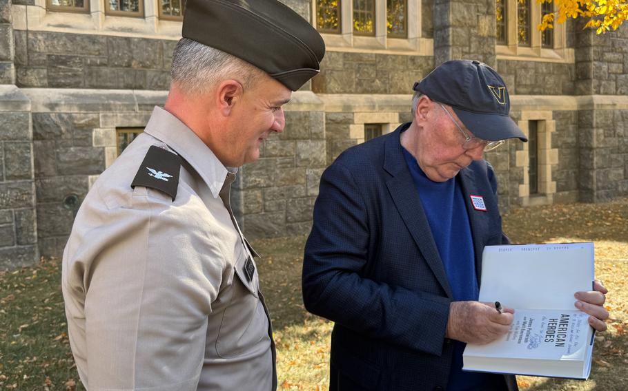 Author James Patterson signs the inside of his new book, “American Heroes,” for a service member