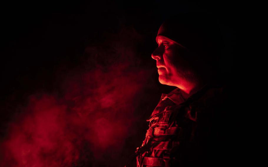 U.S. Army major is illuminated in red as he observes a night artillery fire with the M270A2 Multiple Launch Rocket System.